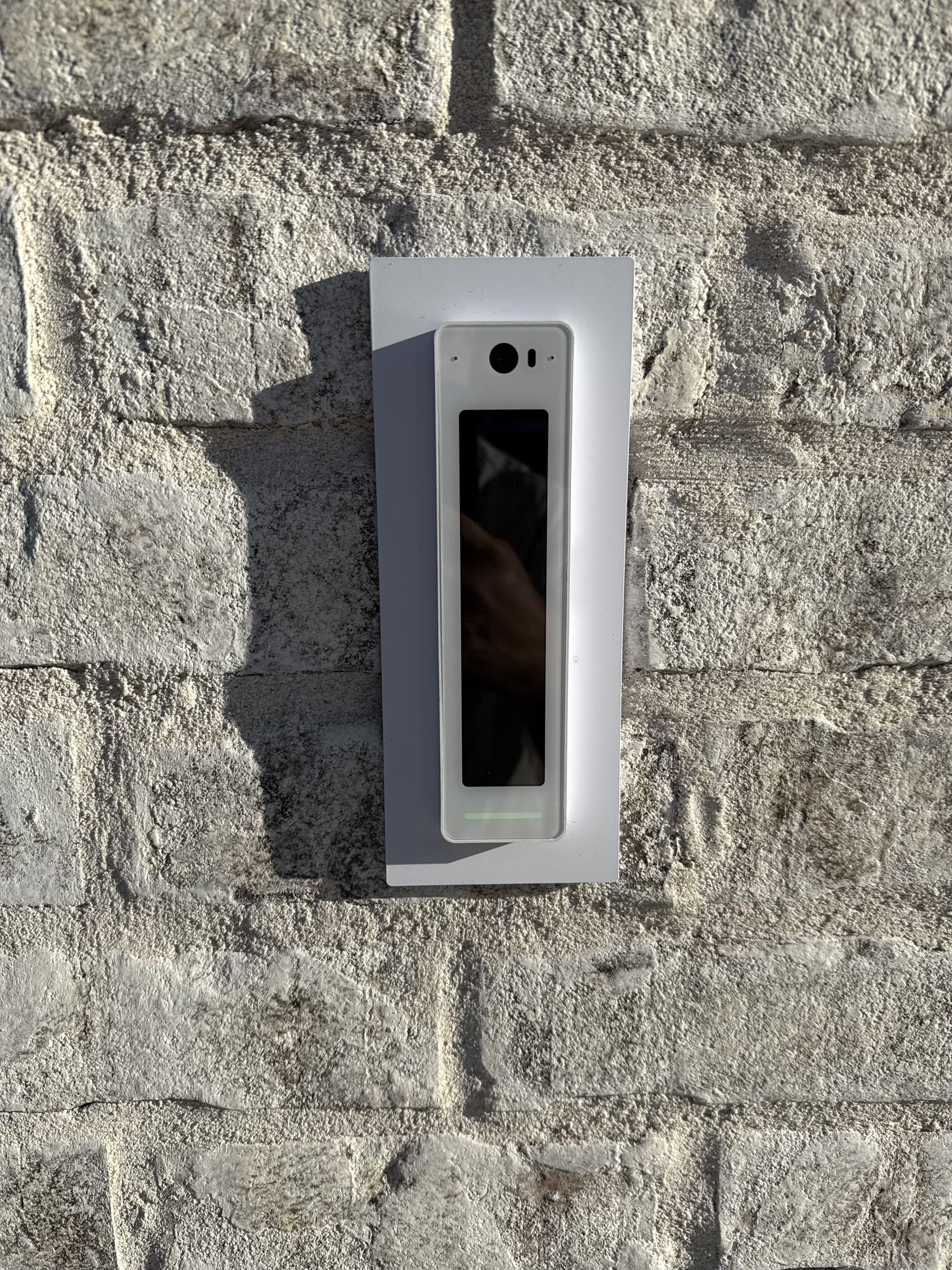 A UniFi Access reader mounted on a stone storefront for keyless door entry